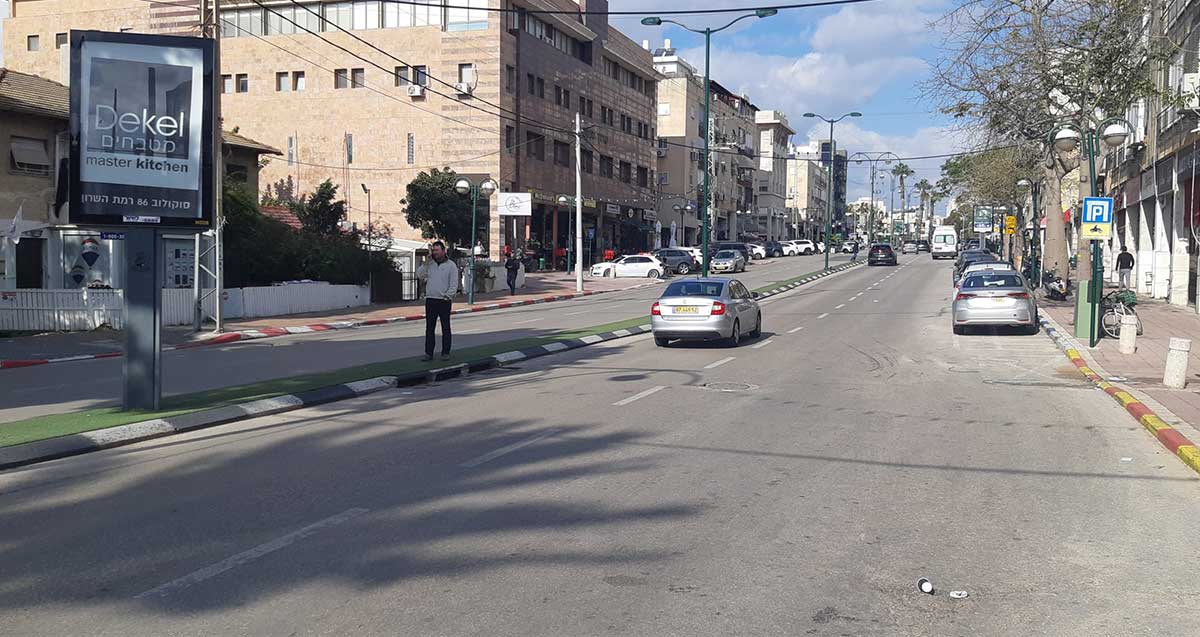 איש צועד בשטח ההפרדה בין נתיבי הנסיעה ברחוב סוקולוב ברמת השרון