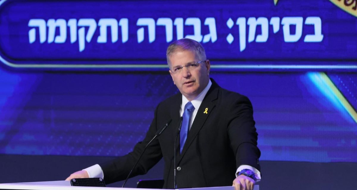 יואב קיש. שר החינוך. מאחוריו שלט: בסימן: גבורה ותקומה