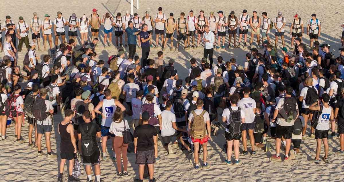 הכנה לגיוס בחוף הרצליה. הנערות והנערים עומדים במעגל ובמרכז שלושה מדריכים.