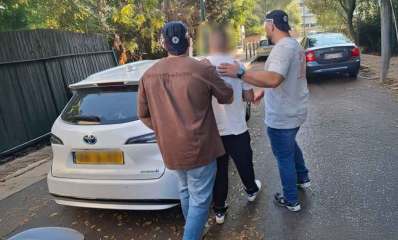 מעצר החשוד בהפצת דוחות חנייה מזויפים. שני שוטרים עוצרים את החשוד ליד רכב לבן.