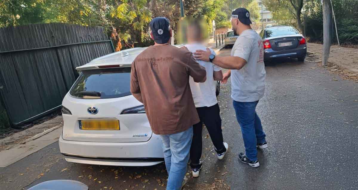 מעצר החשוד בהפצת דוחות חנייה מזויפים. שני שוטרים עוצרים את החשוד ליד רכב לבן.