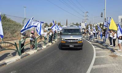 תושבי רמת השרון עומדים לצידי הדרכים ומנופפים בדגלי ישראל בעת מסע ההלוויה של איתי חן זל