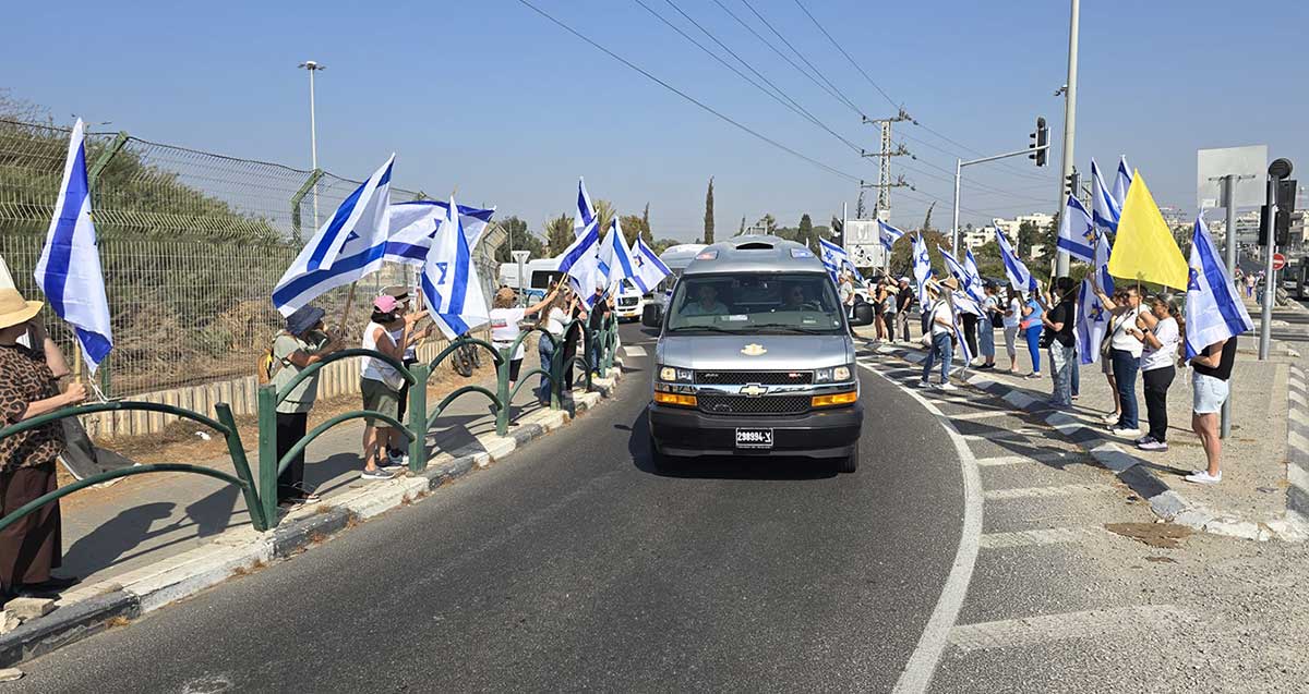תושבי רמת השרון עומדים לצידי הדרכים ומנופפים בדגלי ישראל בעת מסע ההלוויה של איתי חן זל