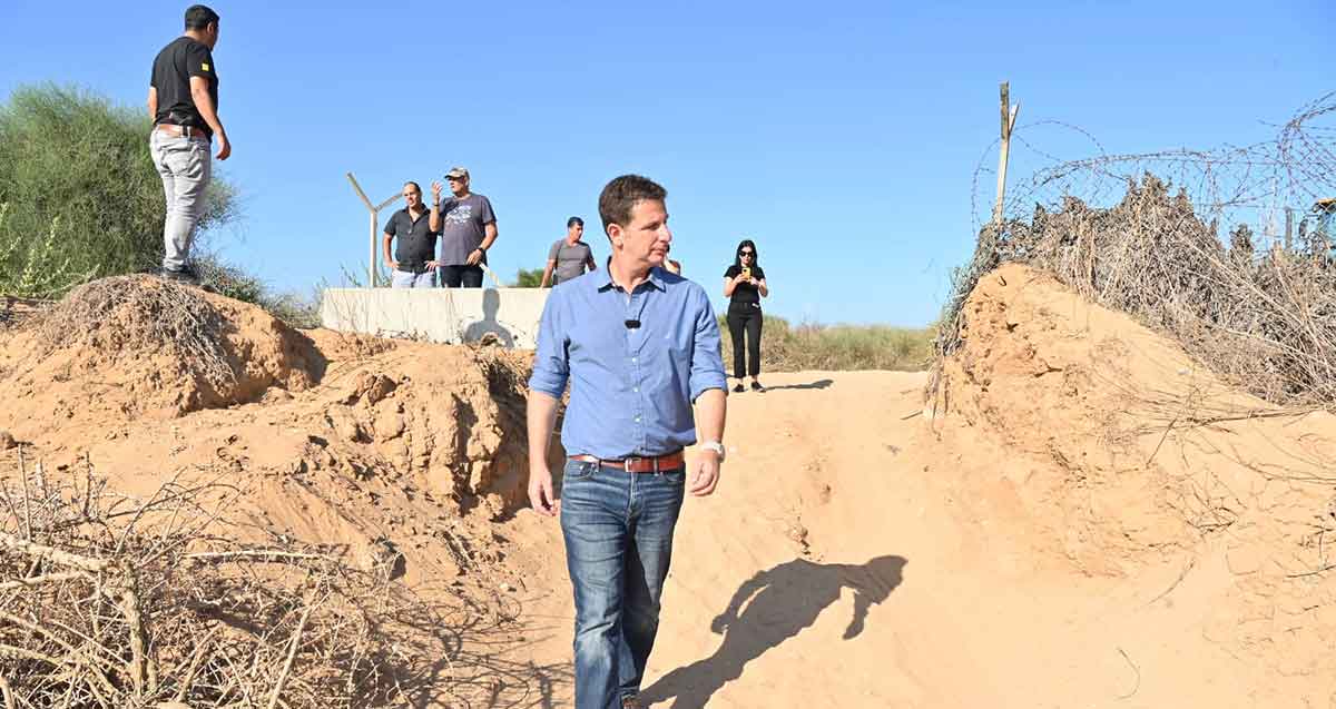 יריב פישר צועד בשביל של חול וברקע מספר אנשים.