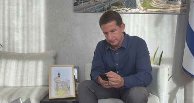 יריב פישר יושב ומתבונן בטלפון שבידיו.