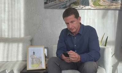 יריב פישר יושב ומתבונן בטלפון שבידיו.