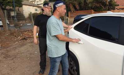 מעצר קטינים החשודים בתקיפה. שני שוטרים ליד דלת של רכב.