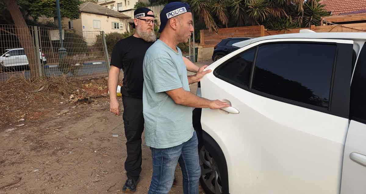 מעצר קטינים החשודים בתקיפה. שני שוטרים ליד דלת של רכב.