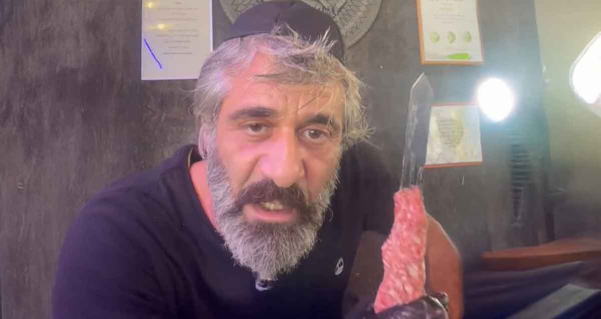 אסף חוג'ה אוחז שיפוד ביד, ובשר על השיפוד.