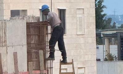 פועל עובד בגובה ללא ריתמה בבית ספר הנדיב בהרצליה. עומד על סולם עץ