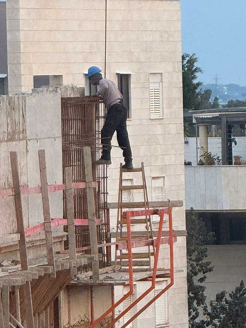 פועל עובד בגובה ללא ריתמה בבית ספר הנדיב בהרצליה. עומד על סולם עץ