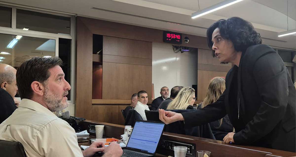 דניאל יעקובי עומד ליד עורך דין עמית גייגר היושב באולם מועצת העיר רמת השרון