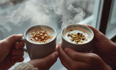 תקריב כפות ידיים של זוג, גבר ואשה, מחזיקים כוסות עם סחלב חם - האחד עם פיסטוק והשני עם בוטנים, הדמיית בינה מלאכותית: השרון אונליין