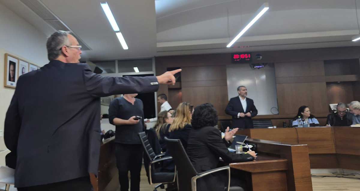 רוכברגר יוצא מאולם ישיבות מועצת העיר רמת השרון. חברי המועצה חלקם יושבים וחלקם עומדים מסביב לשולחן