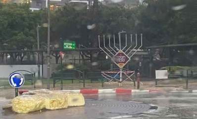 החנוכייה שהדליקה את שכונת נווה גן. חנוכייה גבוהה מוצבת על מדרכה ברחוב הפרחים. במרכזה שלט מעויין עם כיתוב: חנוכה שמח.