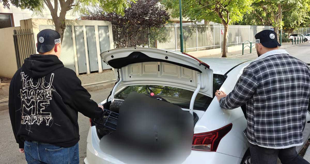 שני שוטרים לבושים על אזרחי עם כובעי זיהוי משטרתיים ליד מכונית