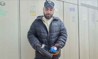 שוטר אוחז אקדח אוויר שנתפס ובקבוק עם נוזל כחול