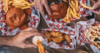 מבט על על שולחן עם מפה לבנה ואדומה מנות המבורגר נאגטס וצ'יפס וידיים של סועדים, צילום: מייסון בורגר