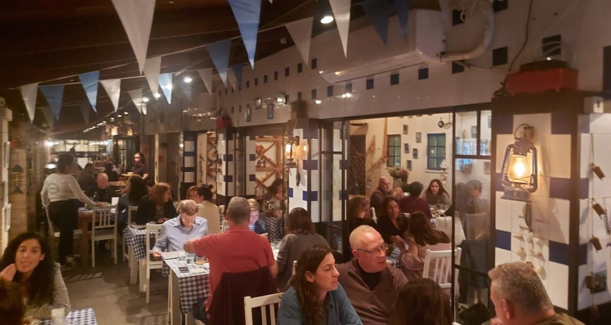 מסעדת זואי בשעות הערב עם דגלונים בכחול לבן וסועדים, צילום: גילי לב-רן