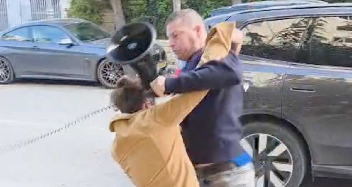 ירון גדות נאבק במפגין. אוחז מגאפון ביד