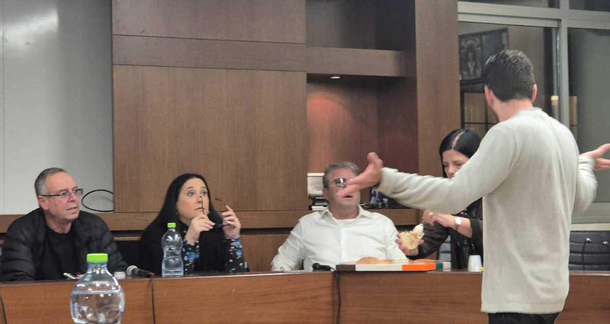 אהד בלייר מסתער לכיוון מרכז שולחן המועצה שבו ישוב בין השאר גם ראש העיר איציק רוכברגר