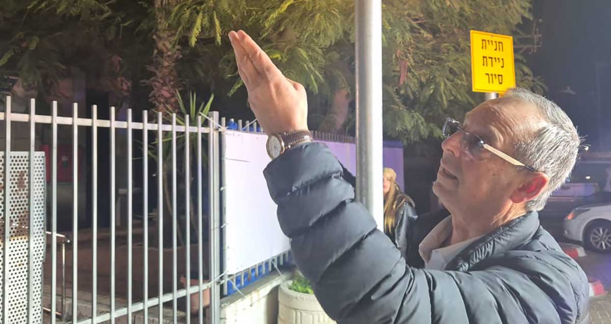 איציק רוכברגר ליד שער המשטרה הנעול מצביע על הבניין התחנה