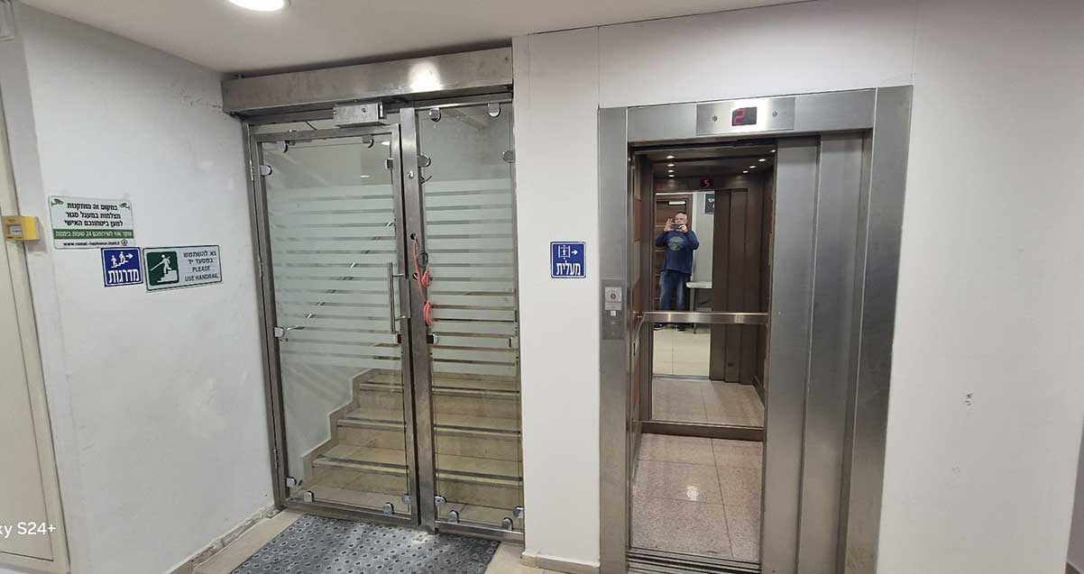 עבודות בינוי על דלת עם זמזם בכניסה לקומת ההנהלה וראש העיר. ליד דלת המעלית