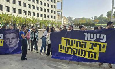 הפגנה של החינוך הדמוקרטי מול בניין העירייה. המפגינים עם שני שלטים גדולים וכיתוב: פישר, יריב החינוך הדמוקרטי!