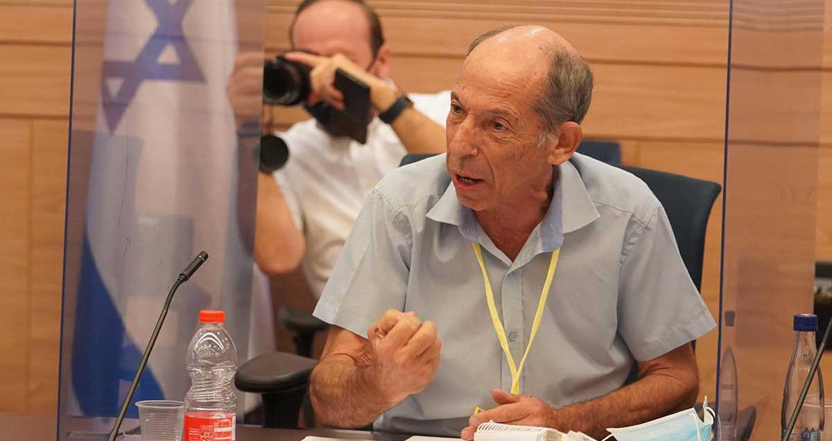 עו"ד ישראל כספי יושב וסרט צהוב תלוי על צווארו.