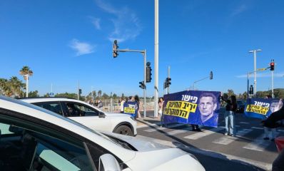 הורים עומדים עם שלטים של הפגנה על מעבר חצייה לפניהם מכוניות פרטיות. צילום: פרטי