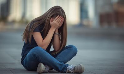 נערה יושבת על הרצפה מכסה את פניה בידיה, הדמיית בינה מלאכותית: שרון אונליין