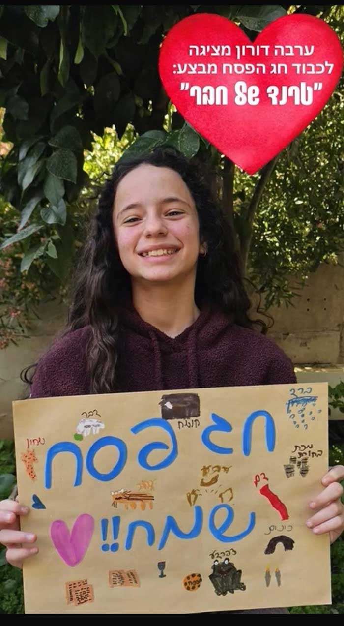 תלמידת כיתה ו׳ ברמת השרון - ערבה דורון מחזיקה שלט חג פסח שמח