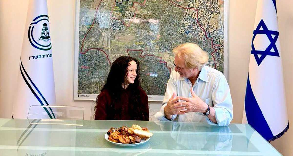 תלמידת בית הספר היסודי גולן, ערבה דורון, עם סגן ראש העיר עידן למדן מאחוריהם דגן רמת השרון ודגל ישראל ומפת העיר רמת השרון