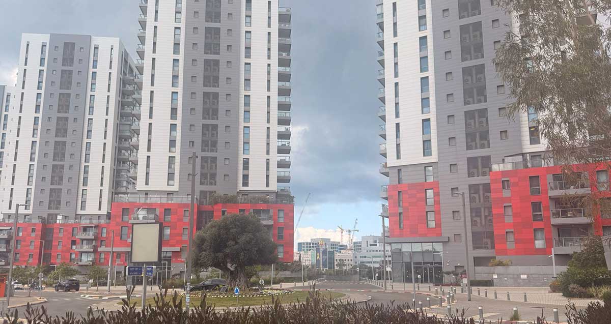 הרצליה הילס. מגדלים גבוהים ושלוש הקומות מעל קומת הרחוב מצופים בחיפוי בצבע אדום.