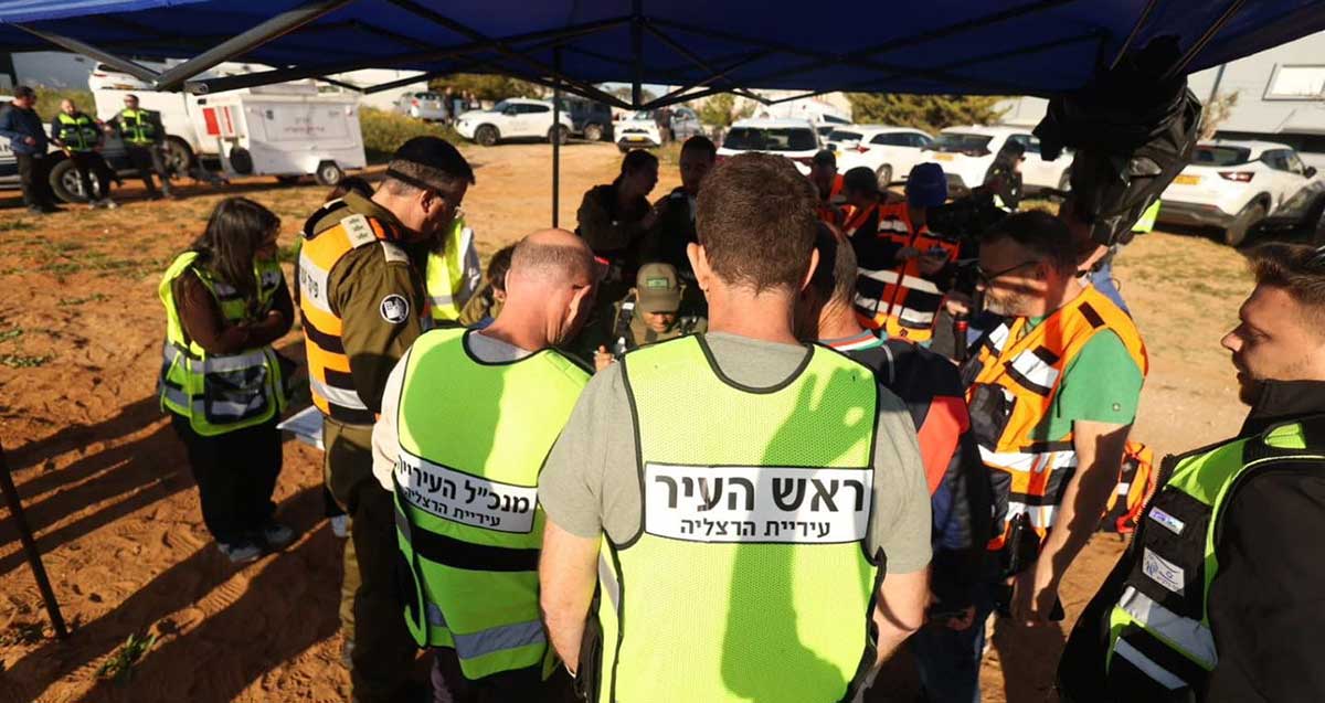 מנכ״ל העירייה אלכס גולדשטיין עם יריב פישר מצולמים מהגב עם ווסטים צהובים בחמל שנפרס בשטח התרגיל