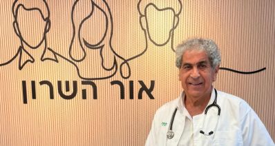 פרופסור עובדי דגן עומד עם חלוק לבן על רקע קיר המרפאה, צילום: כללית