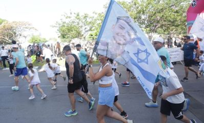 משתתפים במרוץ הרציה 2025 עם דגלי ישראל ותמונות חללי צהל, צילום: דוברות עיריית הרצליה