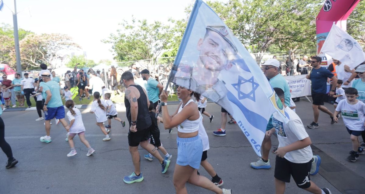 משתתפים במרוץ הרציה 2025 עם דגלי ישראל ותמונות חללי צהל, צילום: דוברות עיריית הרצליה