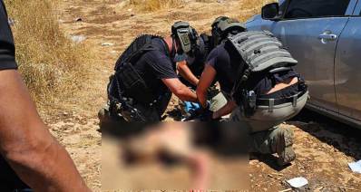 שוטרים של כוחות הביטחון רוכנים מעל אדם בשטח. האדם מטושטש