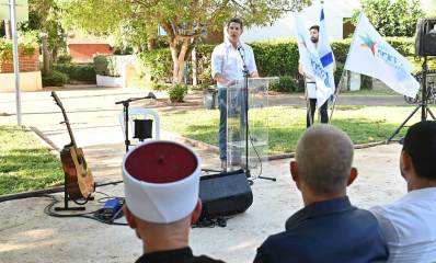 טקס חנוכת גינה ע"ש מחמוד ח'יר אלדין. ראש עיריית הרצליה ליד דוכן הנואמים ומיקרופון, לפני קהל היושב מולו.