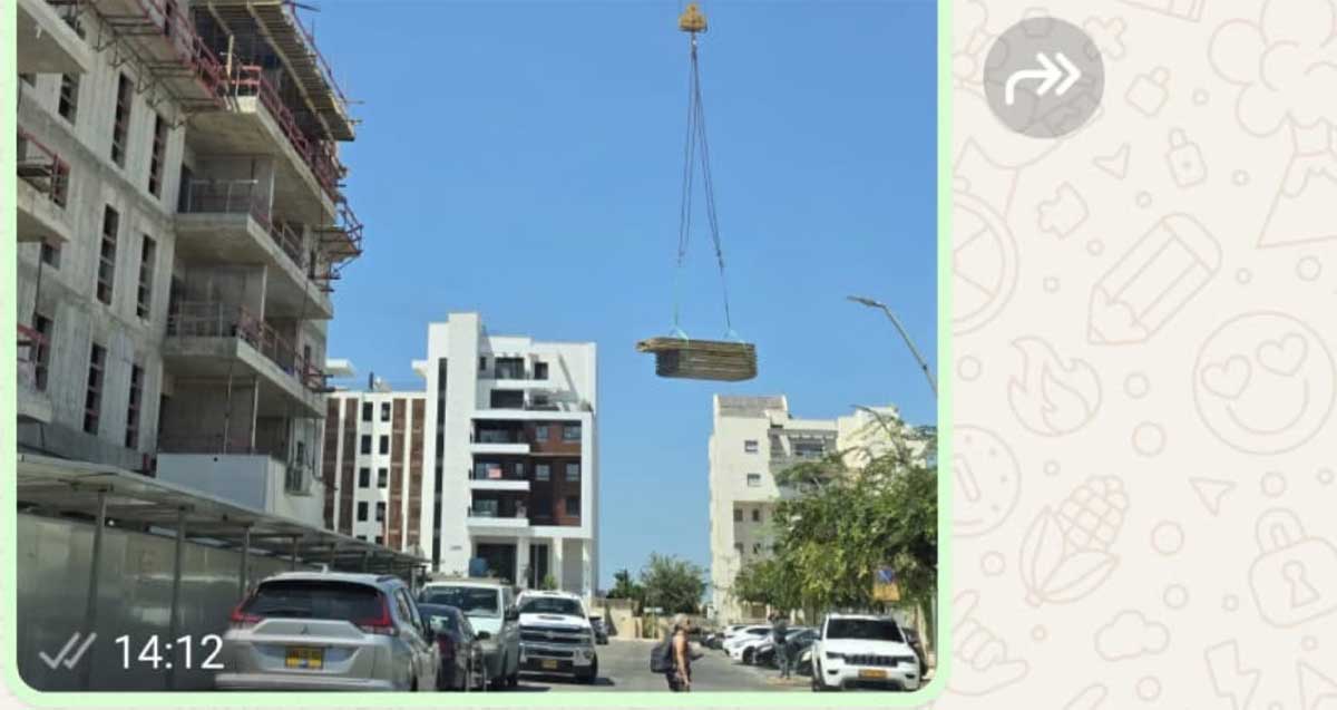 עגורן עם משא כבד מעל רחוב עם הולכי רגל ומכוניות ברעננה