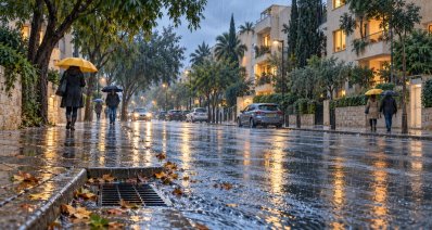 איור של רחוב מגורים ביום חורפי ברעננה, הולכי רגל עם מטריות וכביש רטוב